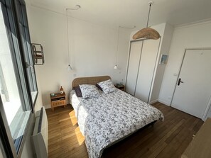 Une chambre à coucher comprenant un lit, des tables de chevet, une armoire et un luminaire suspendu.