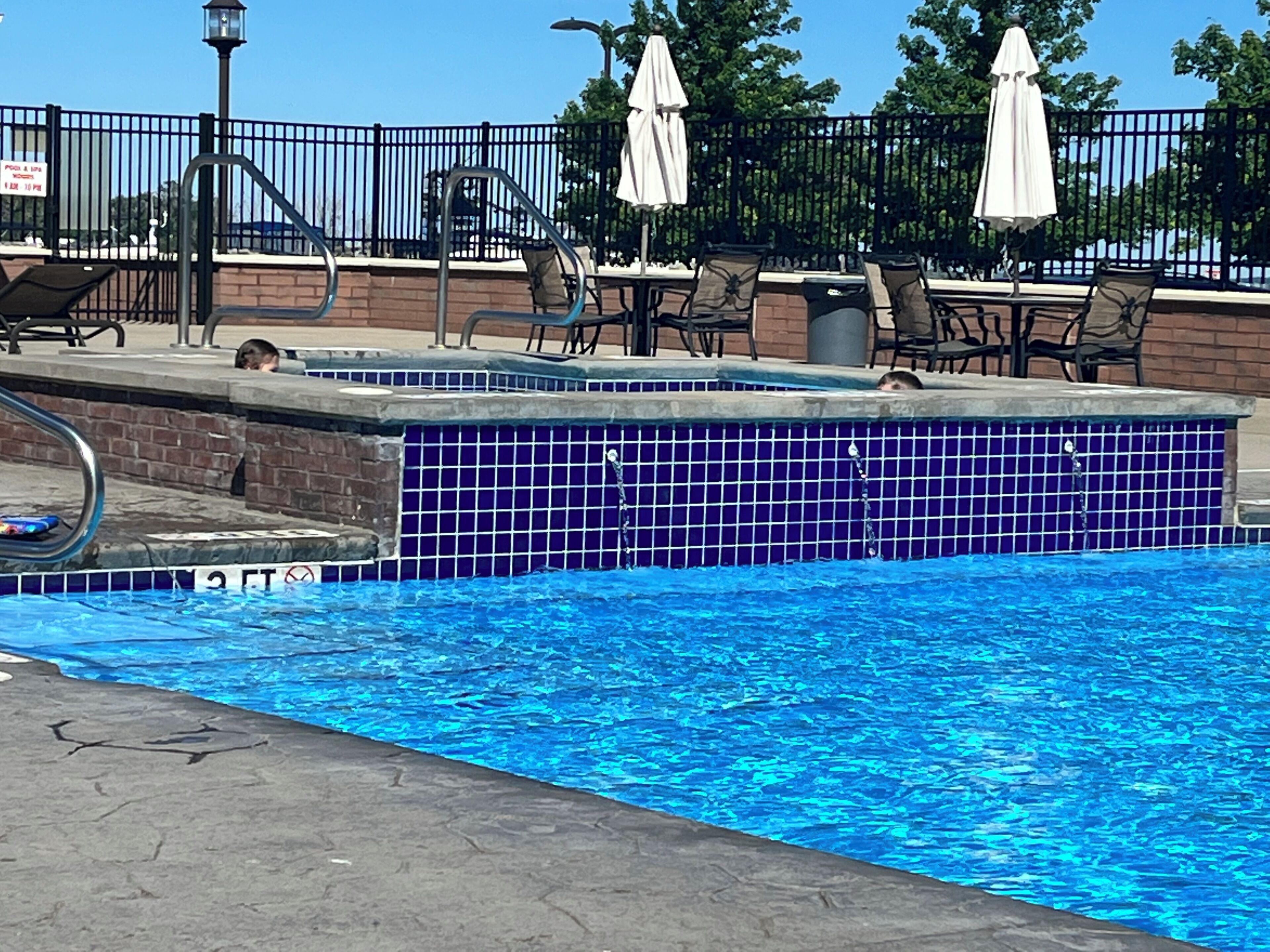 Una piscina amb un videt de rajola, gandules i para-sols.