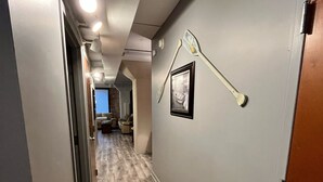 Ein Flur mit Holzboden, einer Tür rechts und einem gerahmten Bild an der Wand.