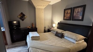 Ein Schlafzimmer mit Bett, Fernseher, Kommode und Nachttisch.