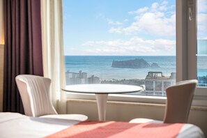 A hotel room with a view of the sea and a distant rocky outcrop. - Shinshin Hotel World Cup (Seogwipo)