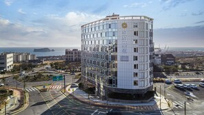 Un hotel moderno con fachada curva, varios pisos y vista al mar.