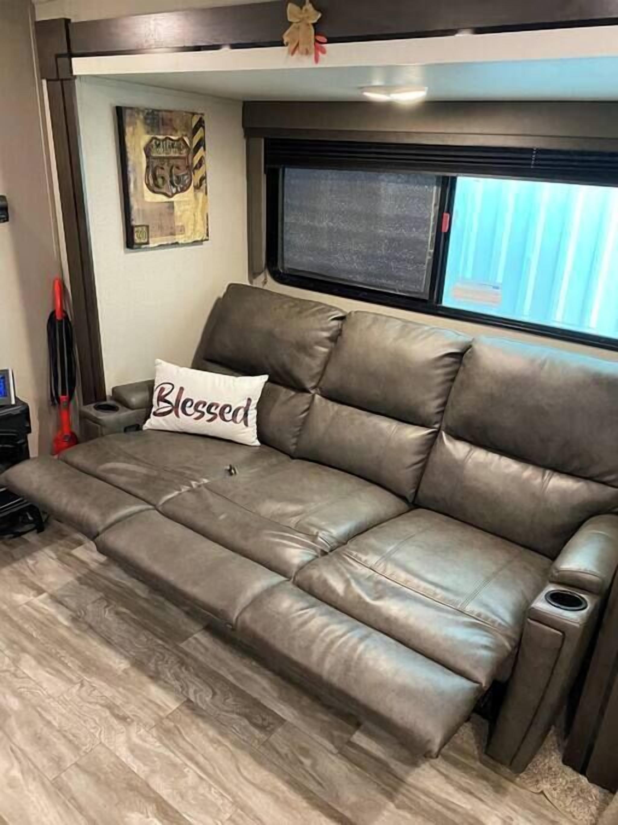 Divano in pelle marrone con un cuscino con la scritta 'Blessed'. Ambiente accogliente all'interno di un camper.