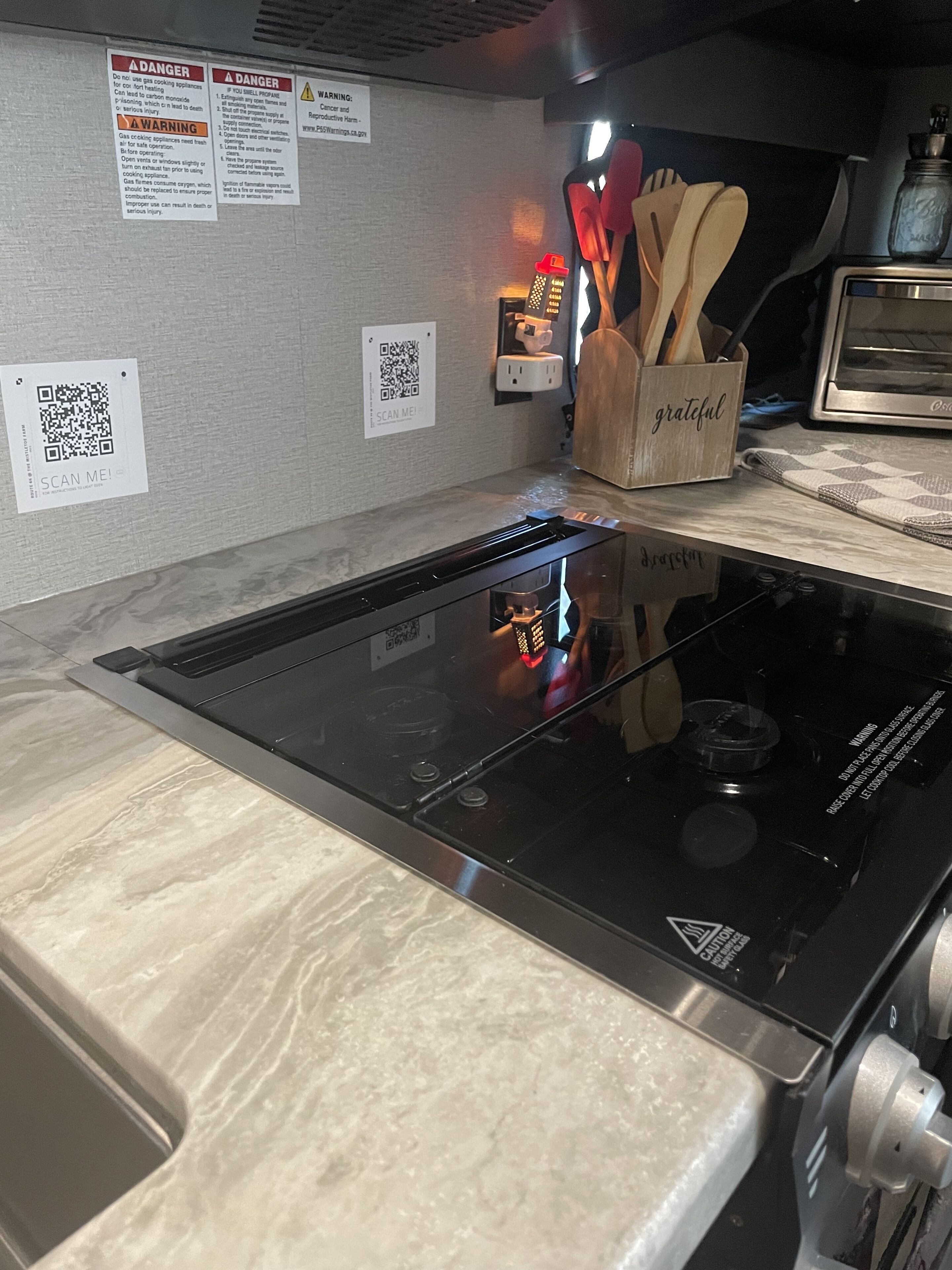 A kitchen with a built-in stove, a QR code, and a wooden utensil holder.