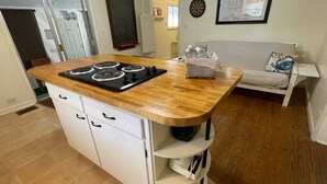 A compact kitchen with a wooden countertop, built-in white cabinets, and a stove. - Charming 1930's house only a few blocks from the St. Johns River! (Welaka)