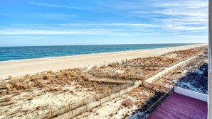 A beach view with a wooden boardwalk and a sandy area with sparse vegetation. - Marigot Beach 303-Oceanfront 101st St, Free WiFi, Pool, Elev, W/D, AC (Ocean City)