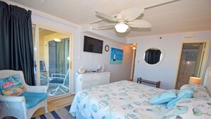 A bedroom with a bed, a chair, a dresser, a television, and a ceiling fan. - Marigot Beach 303-Oceanfront 101st St, Free WiFi, Pool, Elev, W/D, AC (Ocean City)