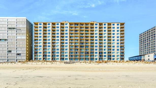 A multi-story hotel with a uniform facade, featuring balconies and a central courtyard. - Marigot Beach 303-Oceanfront 101st St, Free WiFi, Pool, Elev, W/D, AC (Ocean City)