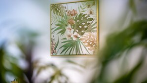 Une œuvre d’art botanique encadrée, avec un cadre doré, représentant des orchidées et des feuilles.