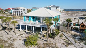 A beachfront house with a balcony, palm trees, and a sandy beach. - Family Friendly with Gameroom! Outdoor swings and more! (Navarre)