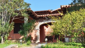 A traditional building with a stone facade, a tiled roof, and a stone archway. - Villette Coda Cavallo (San Teodoro)