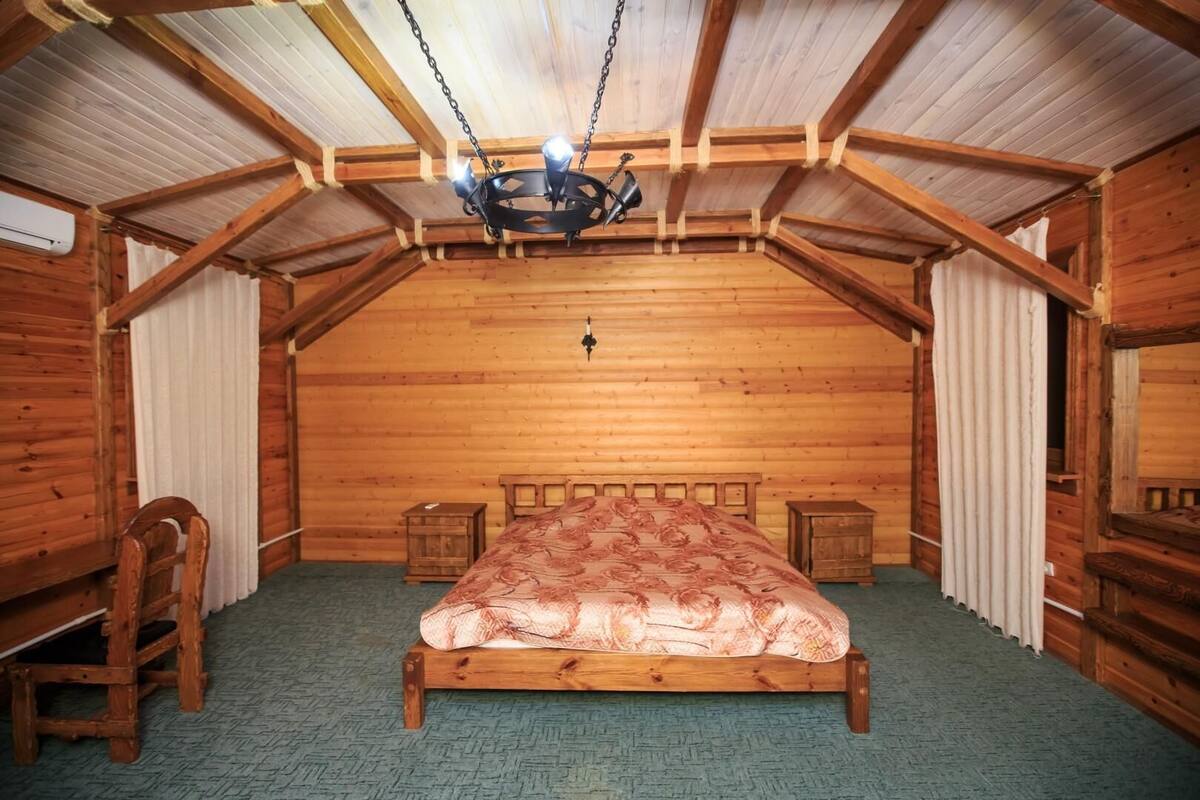 Una habitación de madera con una cama, una silla y una pequeña mesa.