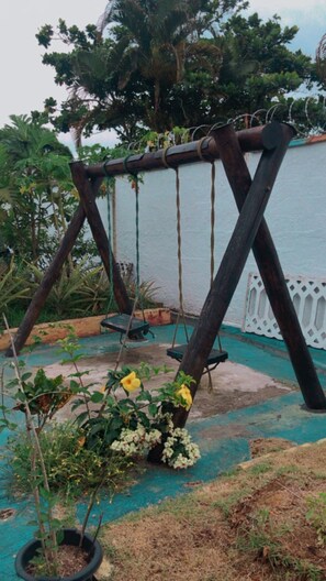A swing set in a garden area with a view of a body of water.