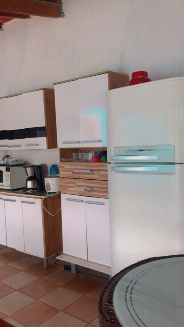 A kitchen with white cabinets, a microwave, a coffee maker, and a refrigerator.