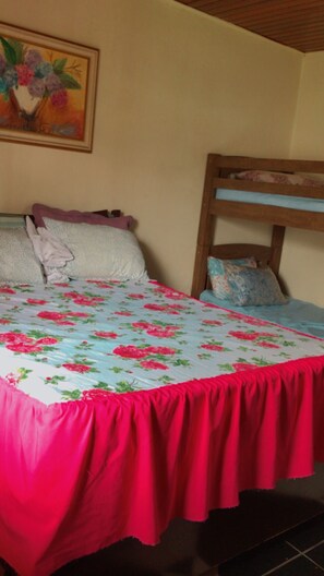 A bed with a floral bedspread, a wooden headboard, and a painting on the wall.
