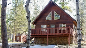 A wooden cabin with a stone foundation, a balcony, and a large window. - 3-Level Spacious Cabin w/ Pool Table, Foosball, Close to Terry Peak & Skiing (Lead)
