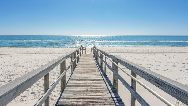 A wooden pier leading to a beach with clear skies. - Pet Friendly Gulf View Townhome | Sleeps 10 | Game Room (Pensacola Beach)