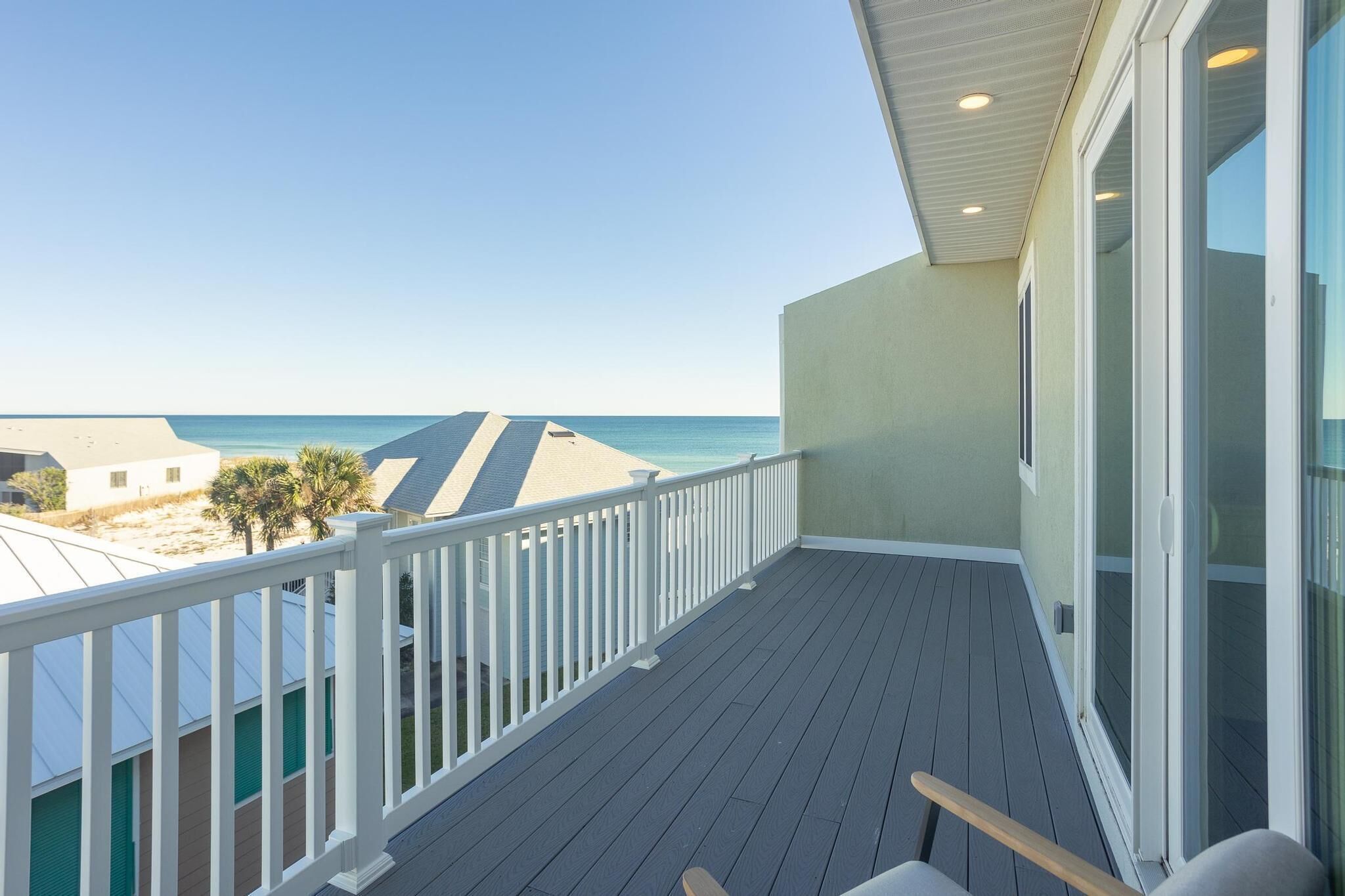 A balcony with a view of the beach and ocean.