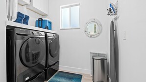 A compact laundry room with a washing machine, dryer, and a small trash bin.