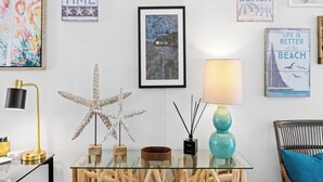A room with a glass table, wooden decor, a starfish sculpture, and beach-themed wall art.