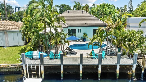 A waterfront property with a swimming pool, deck chairs, and a dock.