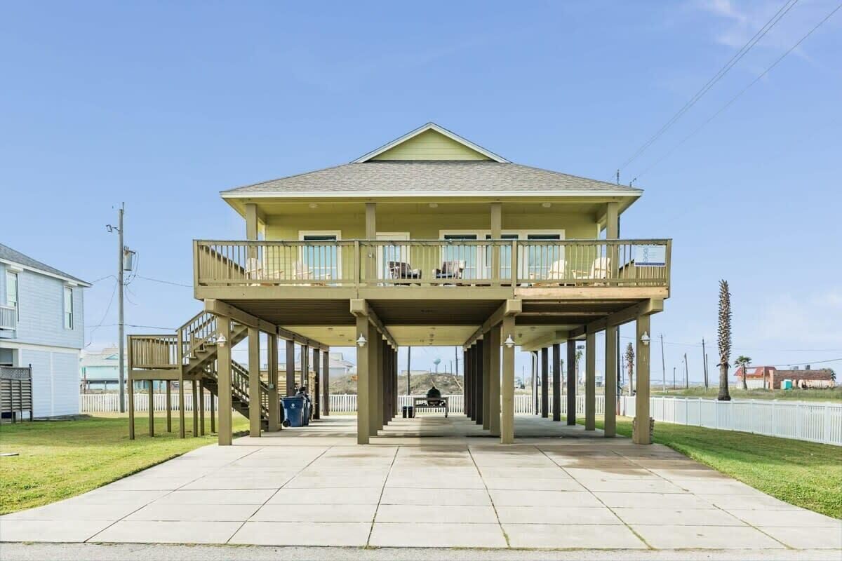 A two-story house with a balcony, a covered porch, and a staircase leading to the upper floor.
