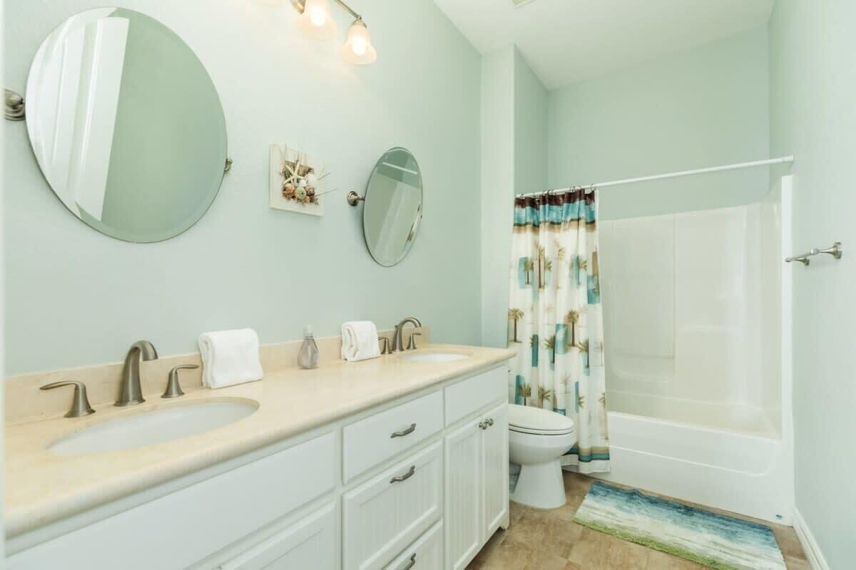 A bathroom with a sink, two mirrors, a toilet, and a bathtub.