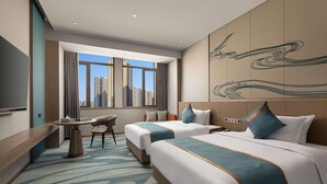 Habitación de hotel con dos camas, un escritorio y vistas a edificios altos.