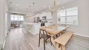 A modern kitchen with white cabinets, a central island, and pendant lighting. - Upgraded! Stunning Pool, Stylish Decor! Kona Cove Retreat, Prime Disney! (Davenport)