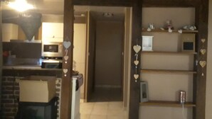 A kitchen with a microwave, a sink, and a refrigerator. There is a wooden shelf with heart-shaped decorations.