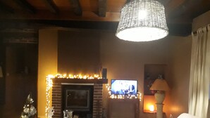 A cozy living room with a fireplace, a television, and a Christmas tree.