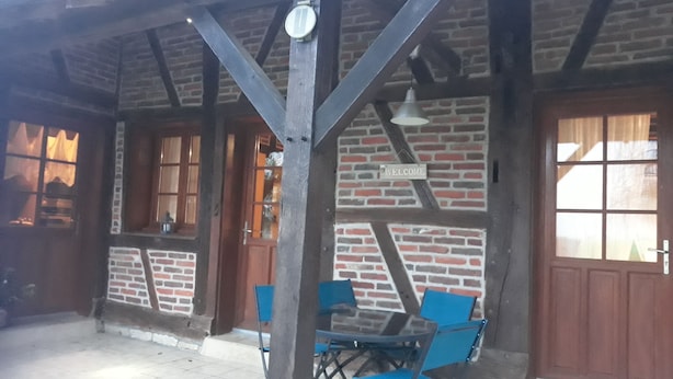 A covered outdoor seating area with a brick wall, wooden beams, and a 'Welcome' sign.