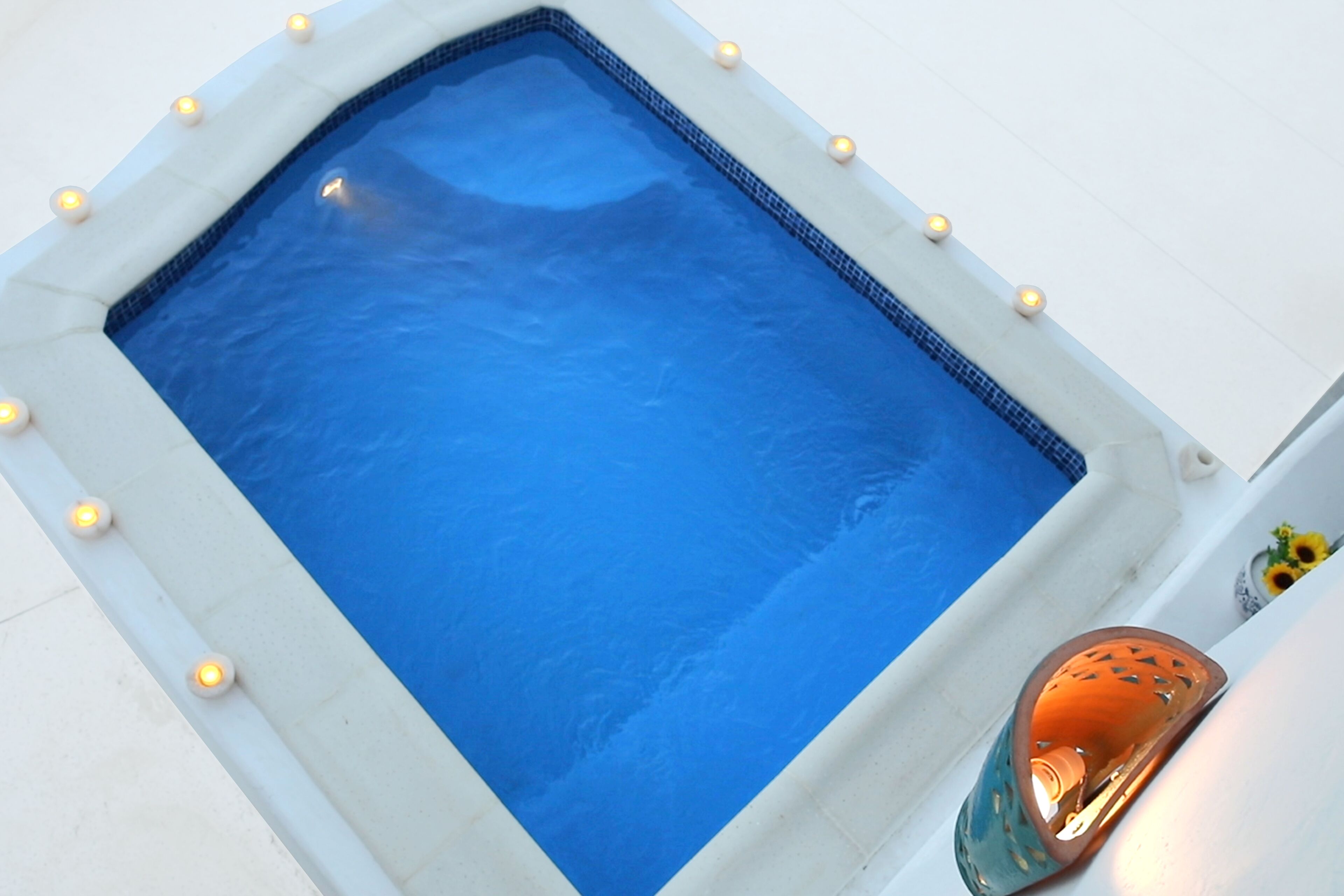 A rectangular pool with a tiled edge and small lights around the perimeter.