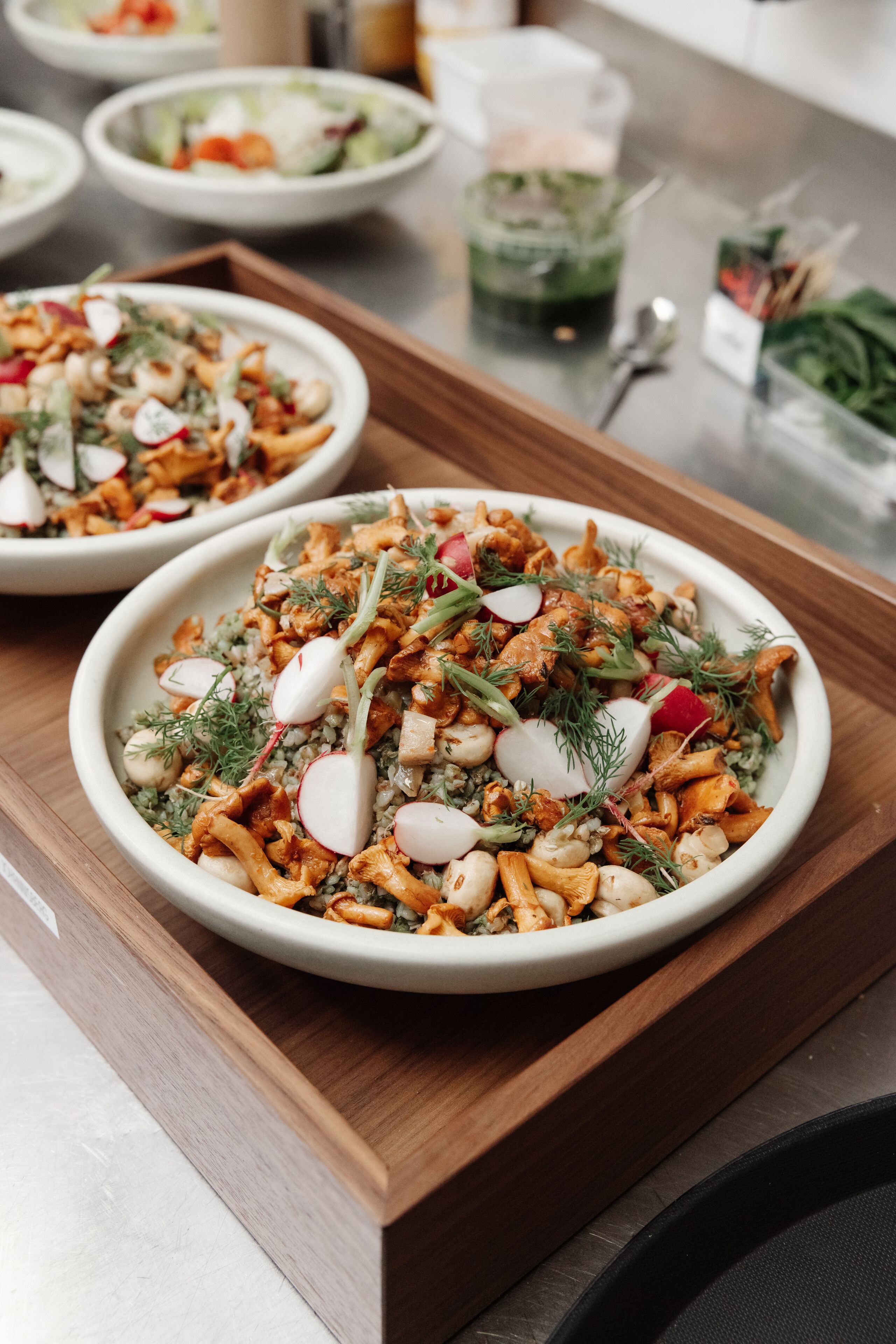 Una mesa de comedor con varios platos, incluyendo una ensalada con rábanos y hierbas, y otros alimentos.