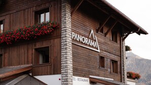 Ein Holzgebäude mit einem Schild, auf dem ‚PANORAMA HOTEL RESTAURANT‘ steht.