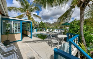 A poolside area with lounge chairs, a table, and a covered seating area.