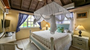 Un dormitorio con cama con dosel, un escritorio con computadora y una ventana con cortinas.