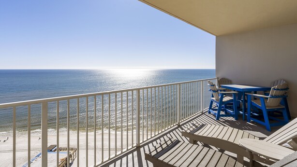 Un balcon avec vue sur l’océan, une table et des chaises.