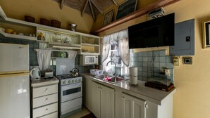 Une cuisine de taille réduite avec des meubles blancs, une cuisinière à gaz, un four à micro-ondes et un évier.