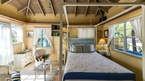 Une chambre à coucher avec un lit, des tables de chevet, une chaise, un bureau et une fenêtre.