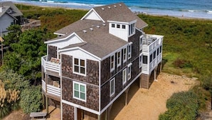 Ein mehrstöckiges Strandhaus mit Balkon, Terrasse und Meerblick.