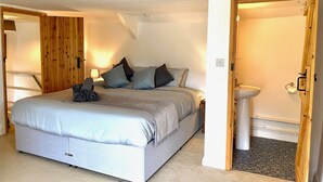 A bedroom with a bed, pillows, a bedside lamp, and a wooden wardrobe. - Charming Cottage for 5 Near Dartmoor, Beach, Pub (Holsworthy)