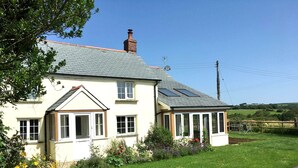 A two-story house with a sloped roof, a chimney, and a small attached garage. - Charming Cottage for 5 Near Dartmoor, Beach, Pub (Holsworthy)