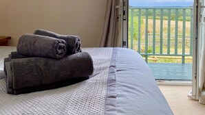 A hotel room with a bed, a painting of animals, and a view of a green landscape through an open door. - Charming Cottage for 5 Near Dartmoor, Beach, Pub (Holsworthy)