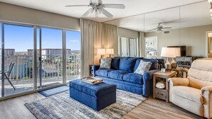 A modern living room with a blue sofa, a beige armchair, and a ceiling fan. - 🌊2BR Seacrest 610-BEST DEAL in Complex-Beachfront without Beachfront Rates🌊 (Fort Walton Beach)