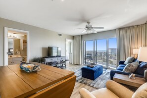 A modern living room with a wooden coffee table, a blue sofa, and a television. - 🌊2BR Seacrest 610-BEST DEAL in Complex-Beachfront without Beachfront Rates🌊 (Fort Walton Beach)