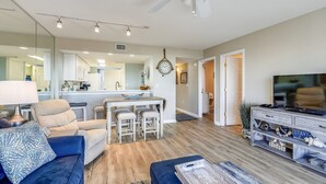 A modern living room with a sofa, ottoman, and a TV stand. - 🌊2BR Seacrest 610-BEST DEAL in Complex-Beachfront without Beachfront Rates🌊 (Fort Walton Beach)