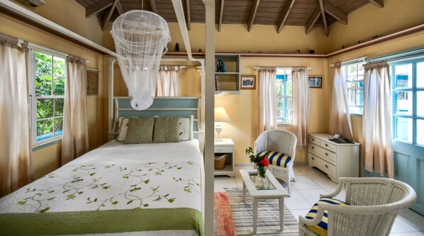 A bedroom with a bed, bedside table, chair, and a hanging light fixture.