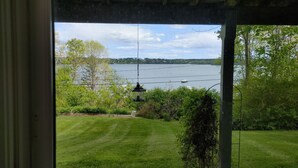 Blick vom überdachten Balkon auf einen See, mit einem Boot auf dem Wasser.