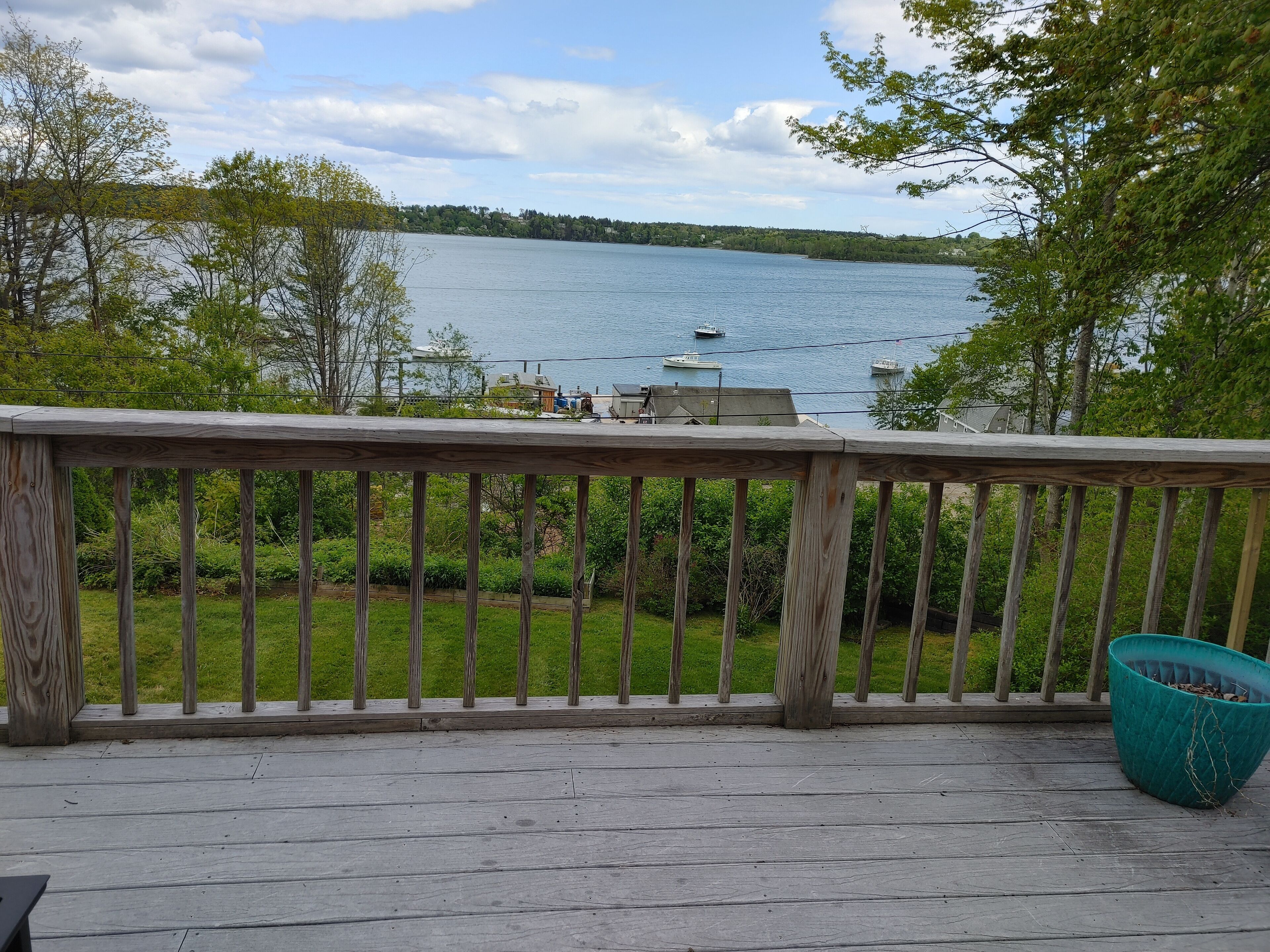A wooden deck with a railing overlooking a lake with boats.